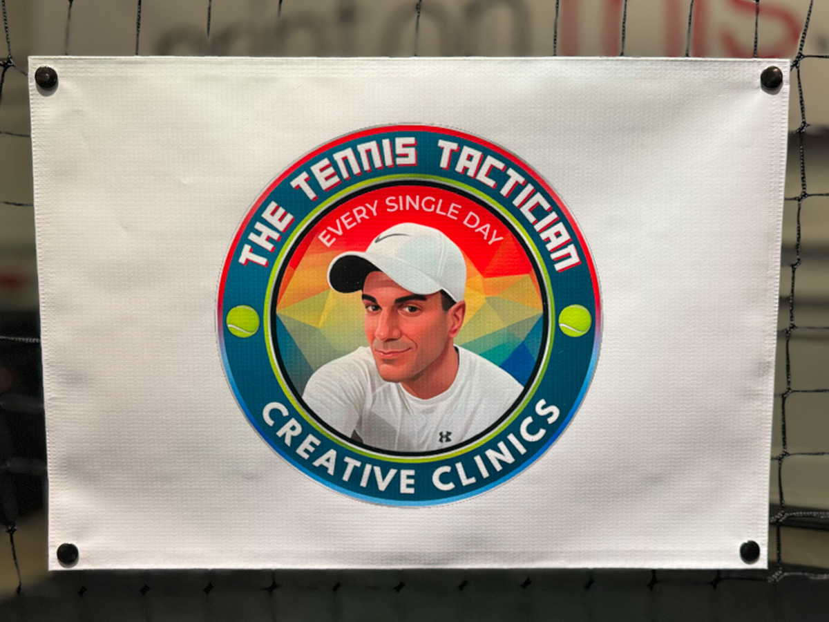 The Tennis Tactician Creative Clinics sponsor banner snapped onto a tennis net
