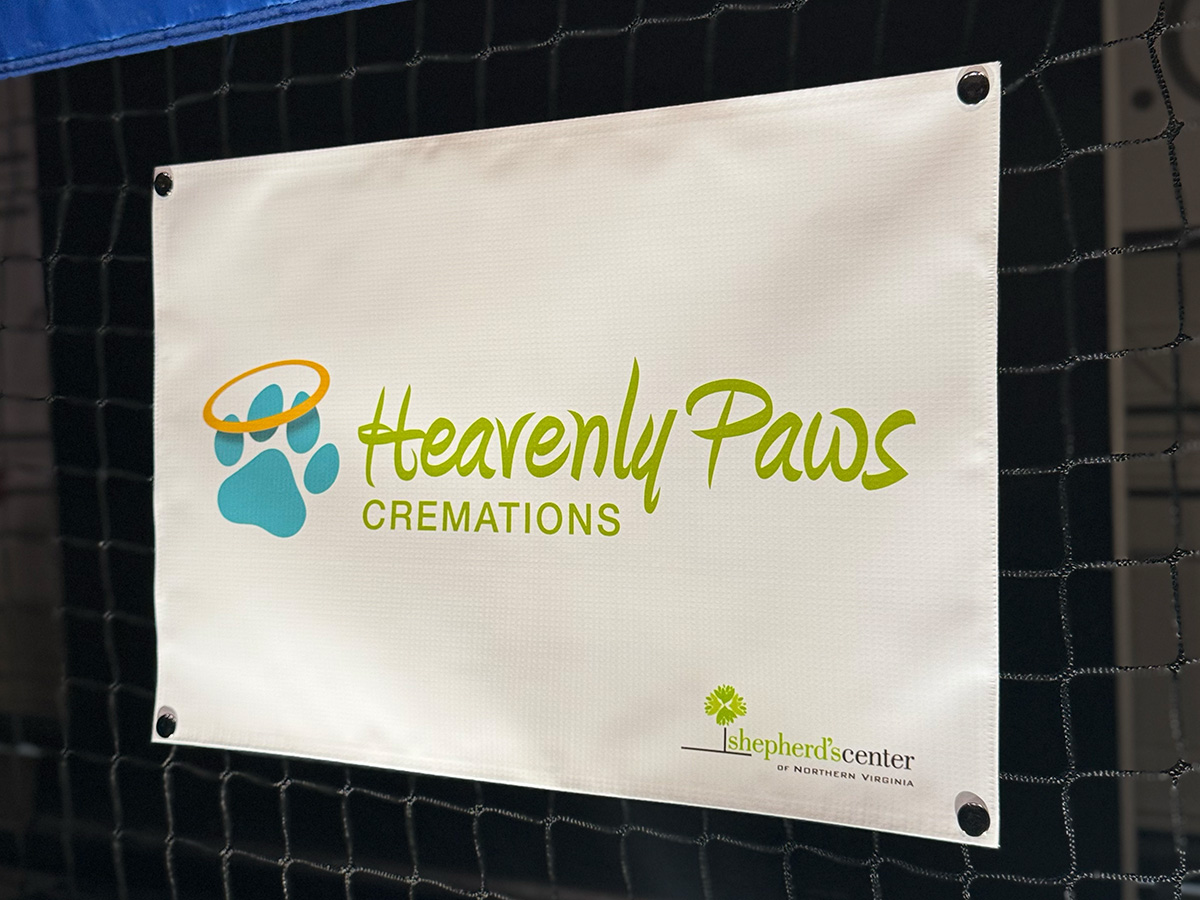 Heavenly Paws Cremations sponsor banner snapped onto a pickleball net